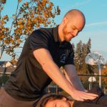 Jason Frederick doing a spinal manipulation on someone smiling lying down.